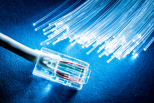Câble réseau et fibres optiques avec lumières sur fond bleu.